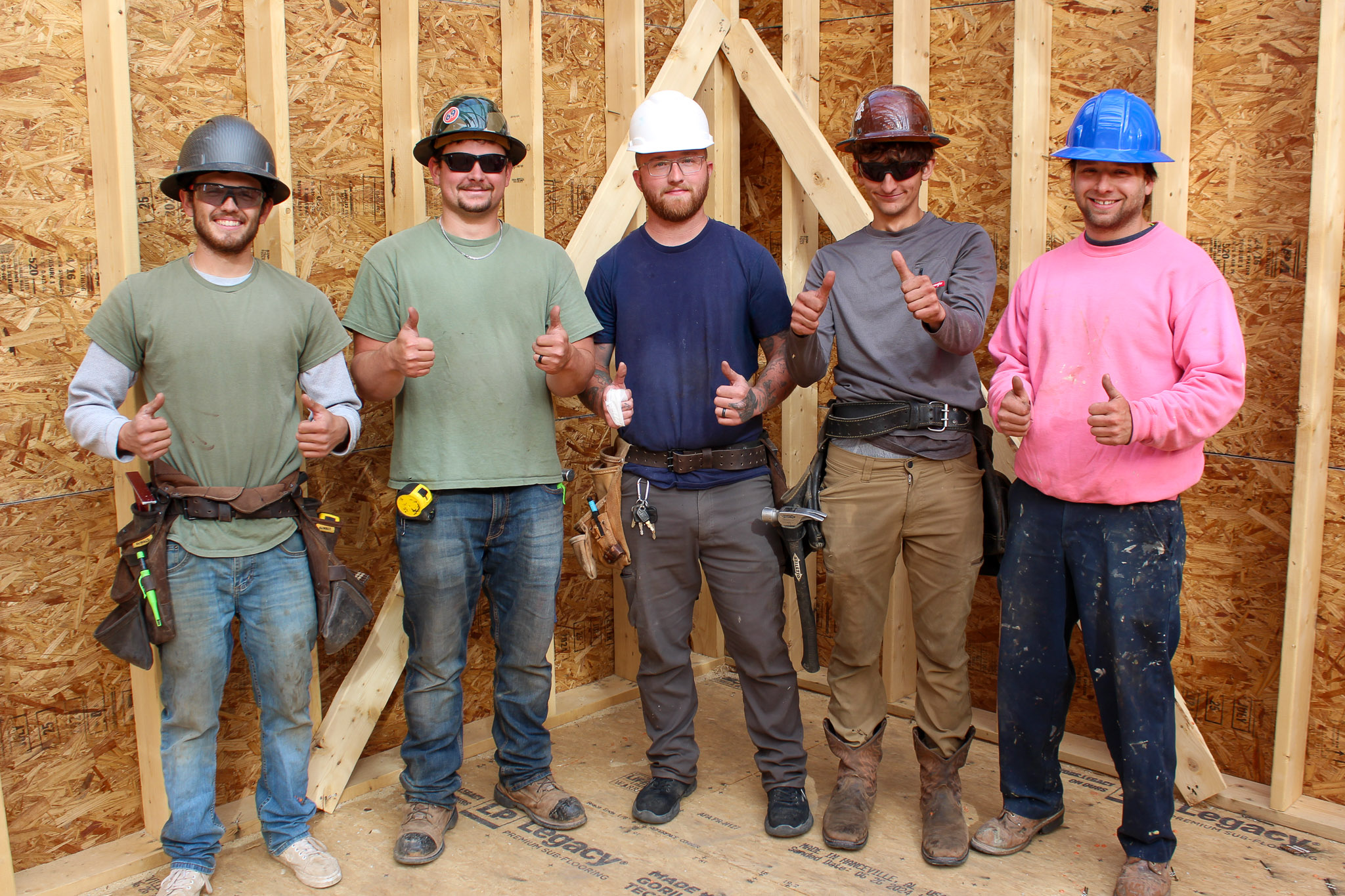 A group of Goodridge Construction home builders standing together inside a newly framed home interior, representing lifestyle homes for teams who build a new house and support clients getting a house built.